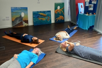 Four people on yoga mats meditating