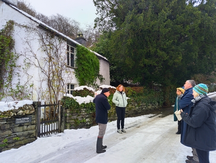 A group of people outside of a small whitewashed cottage in the snow