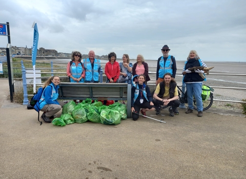 Group of people at coast with rubbish bags 