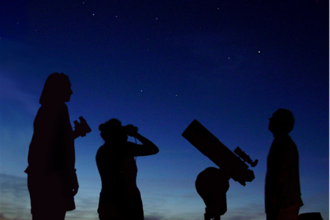 Three people stargazing at dusk.