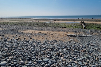 Pebbled beach with sea in distance.