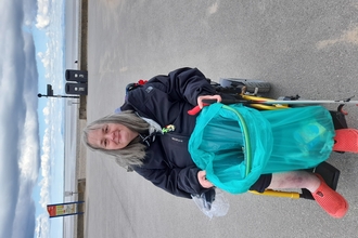 Woman sits in mobility scooter on Fleetwood promenade with bag of litter