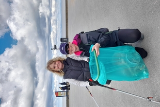 Mum and daughter with bag with litter and litter pickers standing on the promenade at Fleetwood