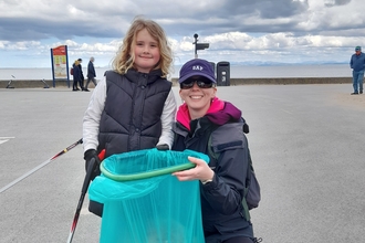 Mum and daughter with bag with litter and litter pickers standing on the promenade at Fleetwood